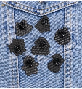 Macro shot of 7 Christmas badge pins showing black rubber backings on blue denim