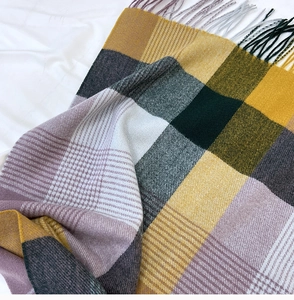 Close-up of mustard yellow and green checkered scarf featuring soft tassel edges