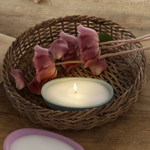 Detail van brandende pastelkleurige keramische kaarsen in een rustieke mand