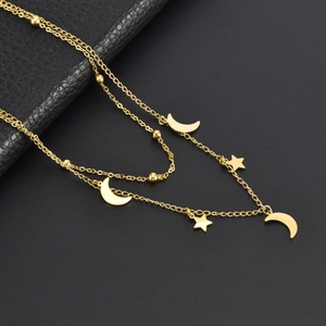 Close-up of double-layer titanium steel necklace with star and moon charms on dark base