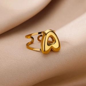 Detailed close-up of bubble-style gold letter A adjustable ring on satin fabric