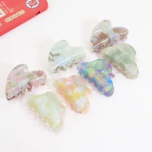 Retro heart-shaped acetate hair claw clips in colorful marble and iridescent textures