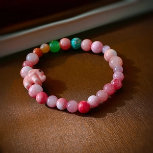 Vue macro du bracelet de perles macaron avec breloque éléphant rose et pierres colorées