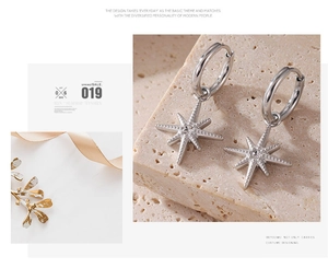 Close-up of silver starburst drop earrings on textured stone with elegant aesthetic