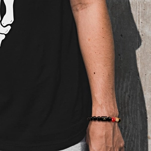 Dettaglio del bracciale intrecciato con ciondolo lettera A indossato sul polso