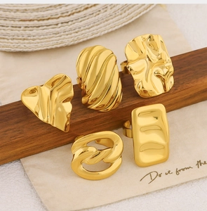 Detailed view of five unique 18k gold-plated geometric rings on rustic wooden stand
