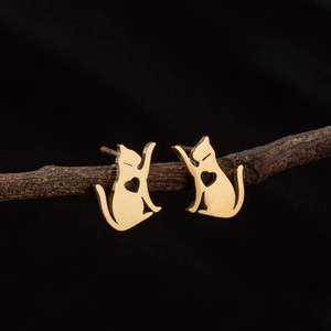Close-up of golden cat stud earrings with hollow heart detail on a branch