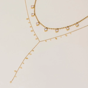 Détail d'un collier doré à plusieurs rangs avec cœurs et pendentifs losanges sertis