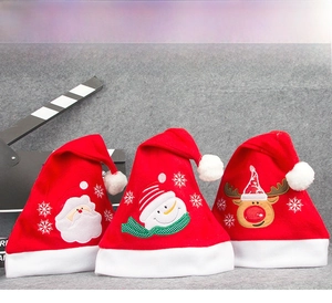 Detailed view of three red velvet Christmas hats with Santa, Snowman, and Reindeer embroidery