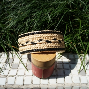 Detailed view of woven raffia headband with black patterns on a wooden glass jar