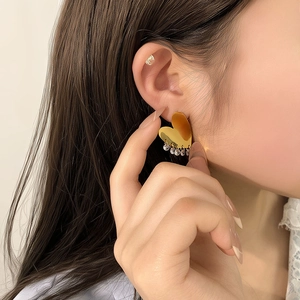 Elegant gold heart earrings with sparkling crystal tassel pendants shown on a model