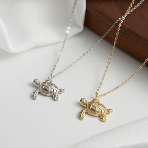 Elegant S925 sterling silver sea turtle necklace with green gemstone eyes on white silk