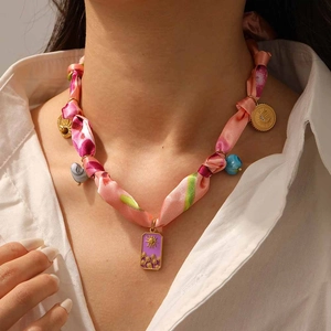 Détail du collier foulard avec pendentifs soleil dorés et breloque en émail violet