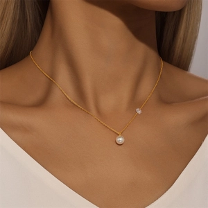Close-up of a minimalist gold Y-necklace featuring a natural pearl and zirconia accent