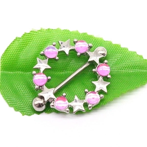 Detail of silver nipple shield with pink opal stones and stars on green leaf background