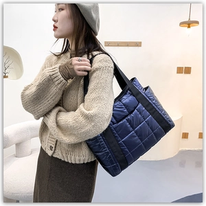Close-up of dark blue quilted puffer tote bag with spacious compartment and soft nylon texture