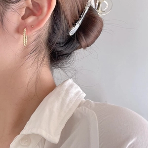 Detailed close-up of golden twisted rope hoop earrings worn for a minimalist style