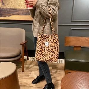 Detalle del bolso tote de pana con estampado de leopardo y etiqueta blanca en atuendo