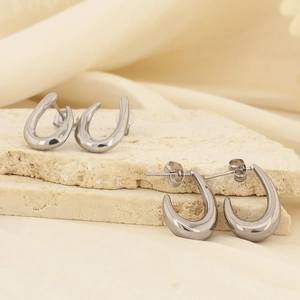 Gros plan de boucles d'oreilles fer à cheval en argent sur pierres et fond en soie élégante