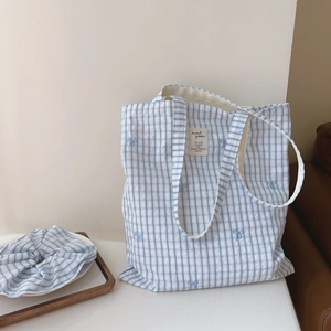 Detailed shot of blue checkered canvas tote bag with embroidered bow and matching scrunchie