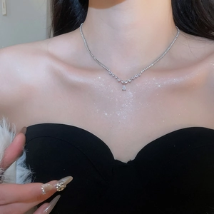 Close-up of elegant V-shaped silver necklace with teardrop zircon pendant on model