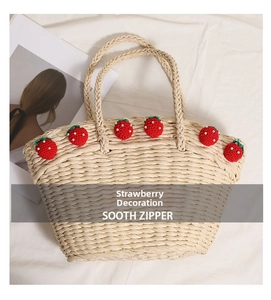Close-up of handmade straw tote bag featuring crochet red strawberries and white pearls