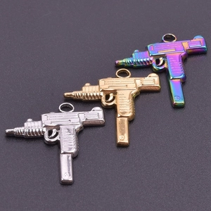 Detailed macro view of Uzi-style gun pendants in gold, silver, and rainbow finishes