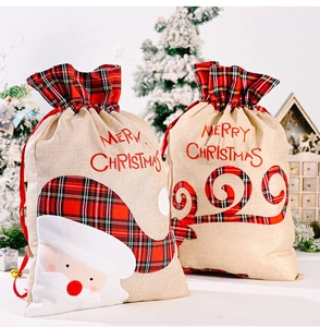Close-up of burlap Christmas gift bags with plaid trim, Santa Claus and reindeer embroidery