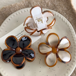 Close-up of three vintage amber floral hair claws in amber, white, black and silver finish