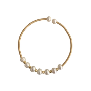 Elegant gold coiled wire open bangle featuring natural freshwater pearls and metal spacers