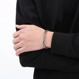 Detailed close-up of a silver Byzantine chain bracelet with a polished metal texture