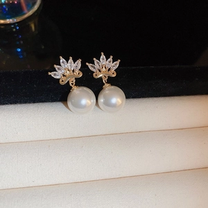 Macro shot of gold plated earrings with sparkling crystals and elegant white pearls