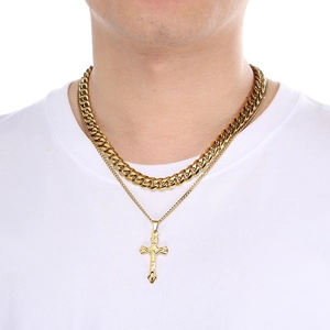 Detail of layered gold stainless steel Cuban chain necklace with cross pendant on model