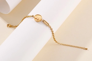 Detailed close-up of golden stainless steel bracelet with cute elephant relief pendant