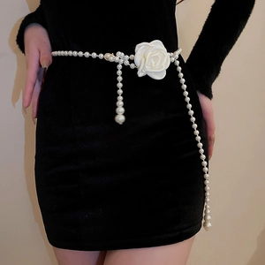 Detail einer luxuriösen Perlen-Taillenkette mit Kamelienblüte auf schwarzem Samtkleid