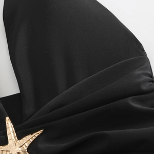 Detail view of black bikini fabric with a golden starfish metal buckle decoration