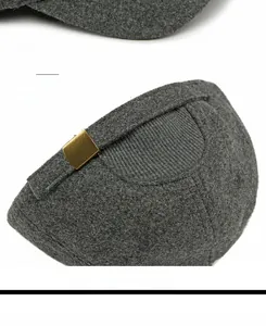 Detailed macro view of dark grey wool cap with copper metal buckle and knit stitching