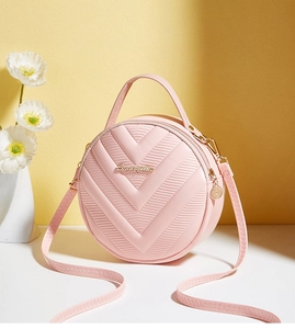 Detailed close-up of a pink round crossbody bag with V-quilted texture and gold logo