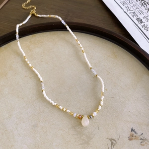 Detail view of handmade beaded necklace with teardrop pendant on traditional paper