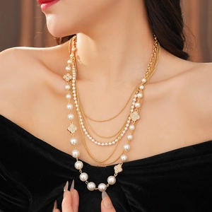 Detailed close-up of multi-layer pearl necklace featuring a clover pendant on model