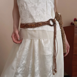 Detail of bohemian hand-woven waist belt with wooden beads on white dress
