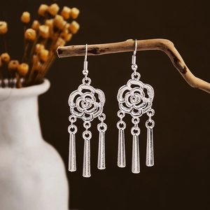 Detail of silver-finish hollow rose earrings with three hanging tassels on a branch