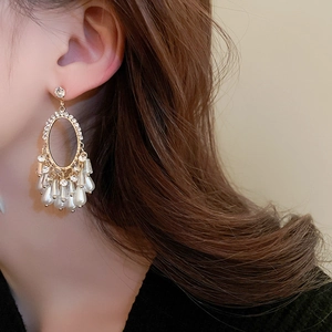 Détail de boucles d'oreilles dorées vintage avec strass ovales et pampilles de perles