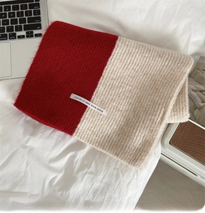 Detail showing plush red and cream knit scarf texture with a stitched fabric label