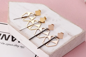 Detail view of geometric titanium steel drop earrings in gold and rose gold finish