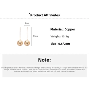 Detailed view of long gold textured ball earrings in copper with dimensions of 6.5x2cm
