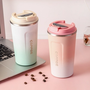Detail showing two gradient 304 stainless steel coffee mugs with flip lids and coffee beans