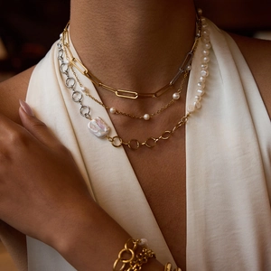 Detail of layered gold and silver chains with baroque pearls and a paperclip link