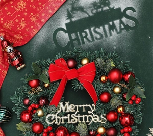 Detail of Christmas wreath with red velvet bow, gold balls, and Merry Christmas sign