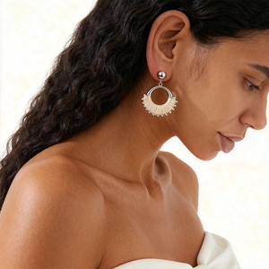 Detail of silver geometric round earrings with beige woven texture on a model
